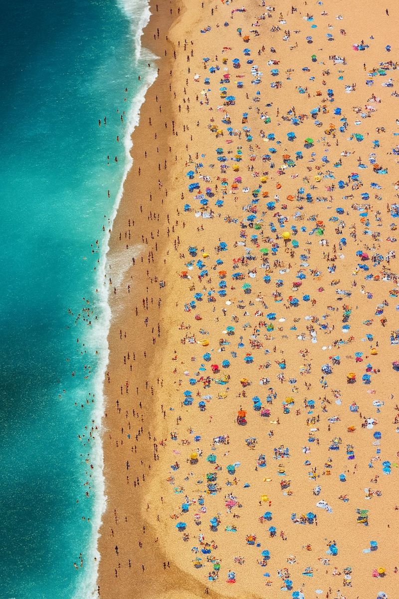 Beach crowd people umbrella sea ocean sky sand summer vacation tourist resort holiday relaxation sunbathing water waves shoreline aerial An aerial view of a crowded beach with many people. The beach is sandy and stretches along the shoreline, with people scattered across the sand. Some are standing, while others are lying down, enjoying the sun. Colorful umbrellas and beach towels dot the landscape, creating a vibrant and lively scene. The water is calm and blue, with waves gently lapping at the shore. The sky is clear and blue, indicating a sunny day.