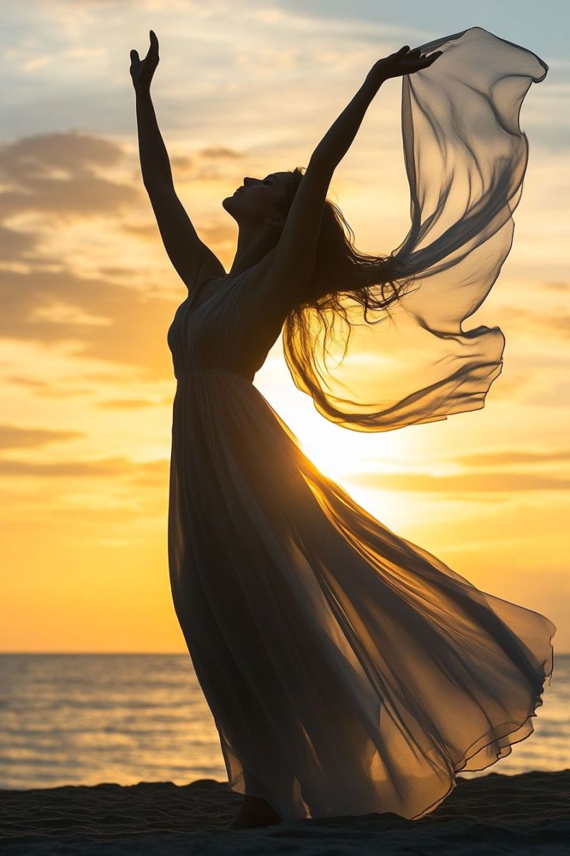 Decors coucher soleil femme dansant mer bras leves fete plage romantique activite loisir soir robe longue cheveux ondulants Dans cette image, une personne se tient debout sur ce qui ressemble à une plage au coucher du soleil. L'individu est vêtu d'une veste en soie et a les bras élevés vers le ciel, comme s'il étreignait ou dansait avec le moment. Ses cheveux semblent être saisisis par la brise, ce qui crée un sentiment de mouvement dynamique. Il est silhouetté contre un ciel éclairé de manière vif et des teintes chaleureuses qui suggèrent que le soleil se couchait ou avait récemment couché. Le fond révèle également ce qui ressemble à du sable sous les pieds et l'horizon où la mer rencontre le ciel. L'humeur générale de cette image pourrait être celle d'une célébration ou d'un joie, indiquant peut-être que la personne est heureuse ou libre dans ce moment-là.