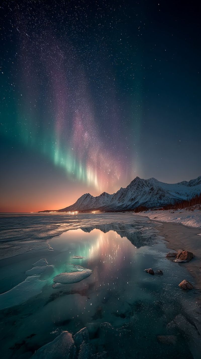 Nuit ciel aurore montagne lac eau reflet neige glace horizon nuages etoiles obscurite beaute nature air L'image capture une scène nocturne à couper le souffle mettant en vedette l'Aurora Borealis, ou Aurores Boréales, illuminant le ciel de teintes vertes et roses vibrantes. Les lumières dansent dans le ciel, créant un spectacle fascinant. En dessous, un plan d'eau serein reflète les couleurs de l'aurore, ajoutant une touche magique à la scène. L'eau est calme, avec des morceaux de glace éparpillés ajoutant de la texture. En arrière-plan, des montagnes enneigées s'élèvent majestueusement, leurs pics en silhouette contre le ciel. L'horizon est peint avec les couleurs douces et chaudes du soleil couchant, créant un contraste saisissant avec les tons frais de l'aurore. L'atmosphère générale est tranquille et impressionnante, mettant en valeur la beauté de la nature dans sa forme la plus pure.