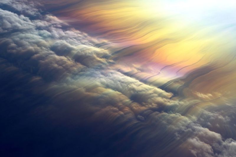 Atmosphere clouds sky sunlight rainbow colorful aerial nature weather horizon reflection pattern texture The image showcases a breathtaking aerial view of the sky, dominated by a vast expanse of clouds. The clouds are thick and puffy, with shades of white, gray, and dark blue. The sky transitions from a deep blue at the top to a lighter blue and yellow near the horizon, creating a gradient effect. The clouds are illuminated by the sun, casting a warm glow on them and creating a beautiful interplay of light and shadow. The overall effect is one of serenity and awe, as if the viewer is floating above the clouds, looking down at the world below.