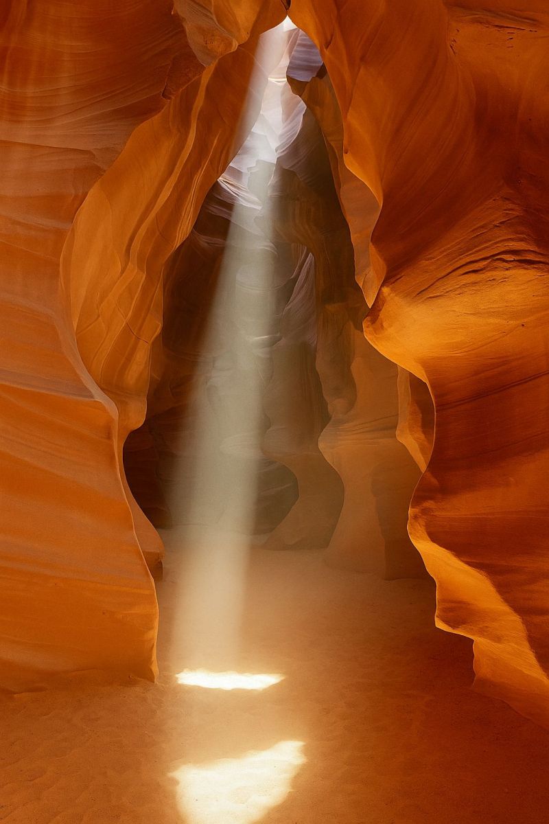 Canyon sunlight sunbeam sun sunrays sunshine A narrow canyon with a beam of sunlight streaming through, illuminating the interior. The canyon walls are made of reddish-brown sandstone, with intricate patterns and textures. The sunlight creates a dramatic effect, casting shadows and highlighting the contours of the canyon. The light beam appears to be coming from a small opening at the top of the canyon, creating a sense of depth and perspective. The overall scene is serene and awe-inspiring, showcasing the beauty of nature.