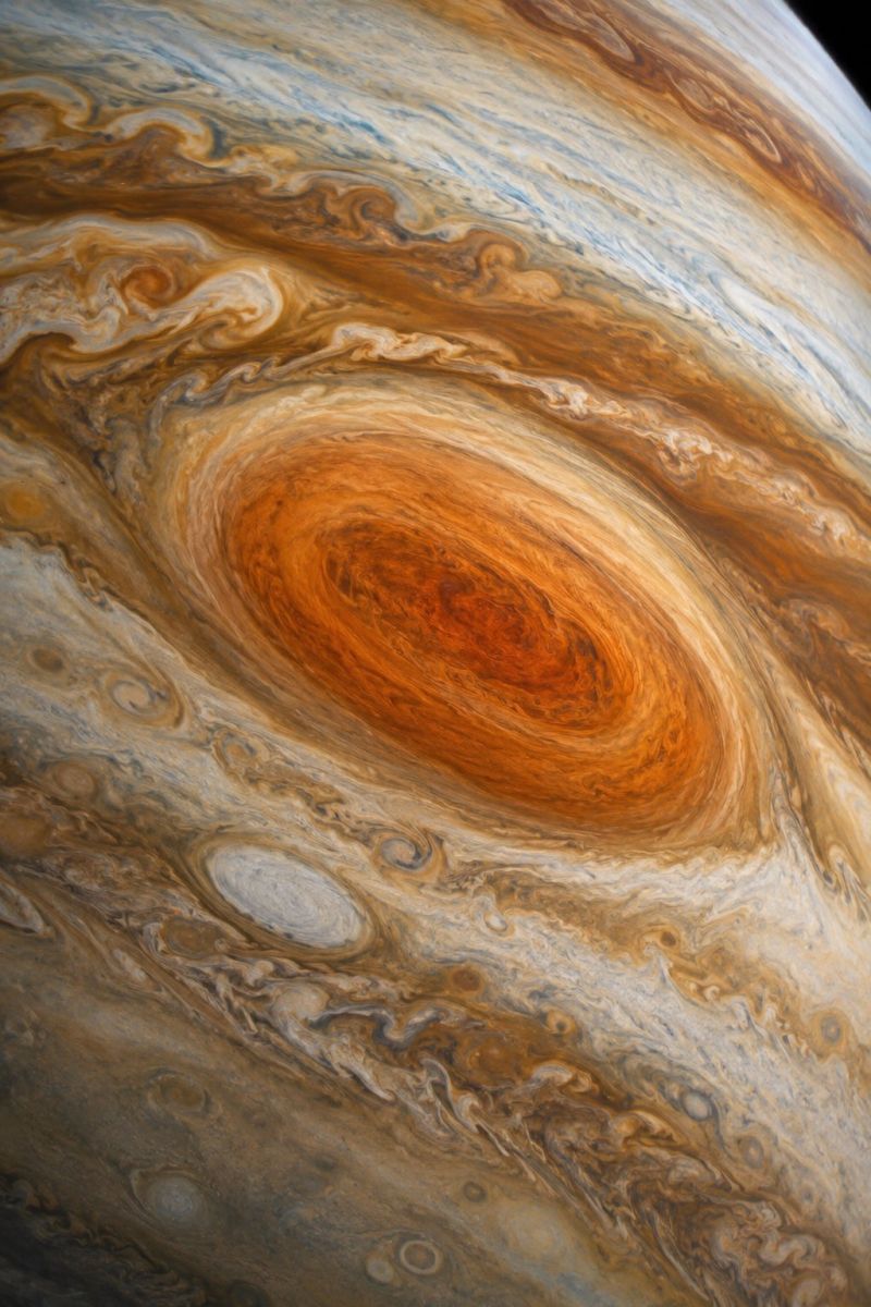 Planet jupiter space astronomy cosmos atmosphere celestial astrophysics universe exploration science telescope orbit satellite astrophotography gas The image showcases a close-up view of Jupiter's atmosphere, dominated by a large, swirling storm known as the Great Red Spot. This storm is characterized by its reddish-brown color and its spiral pattern, which is surrounded by a series of smaller, swirling clouds in various shades of brown, beige, and white. The atmosphere is filled with intricate, wavy patterns and bands, creating a dynamic and textured appearance. The overall scene is vibrant and colorful, with a mix of deep and light tones, highlighting the planet's complex and ever-changing weather systems.